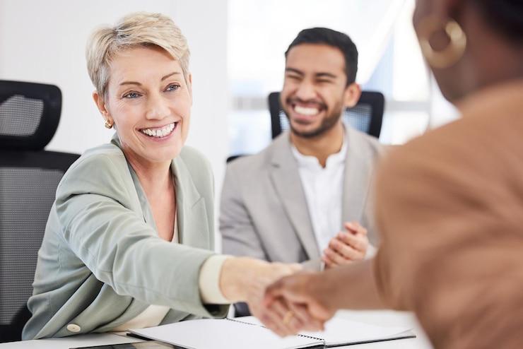 Colleagues shaking hands across a meeting table