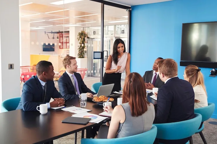Colleagues seated around a table in a blue-walled meeting room